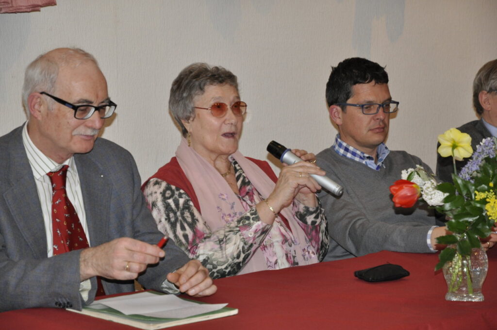 Eine Gruppe von Menschen sitzt an einem Tisch, während eine Person ein Mikrofon hält.