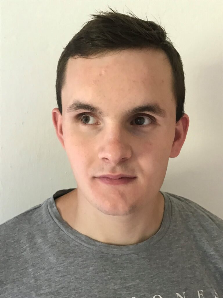 Eine Person mit kurzen dunklen Haaren schaut leicht zur Seite.