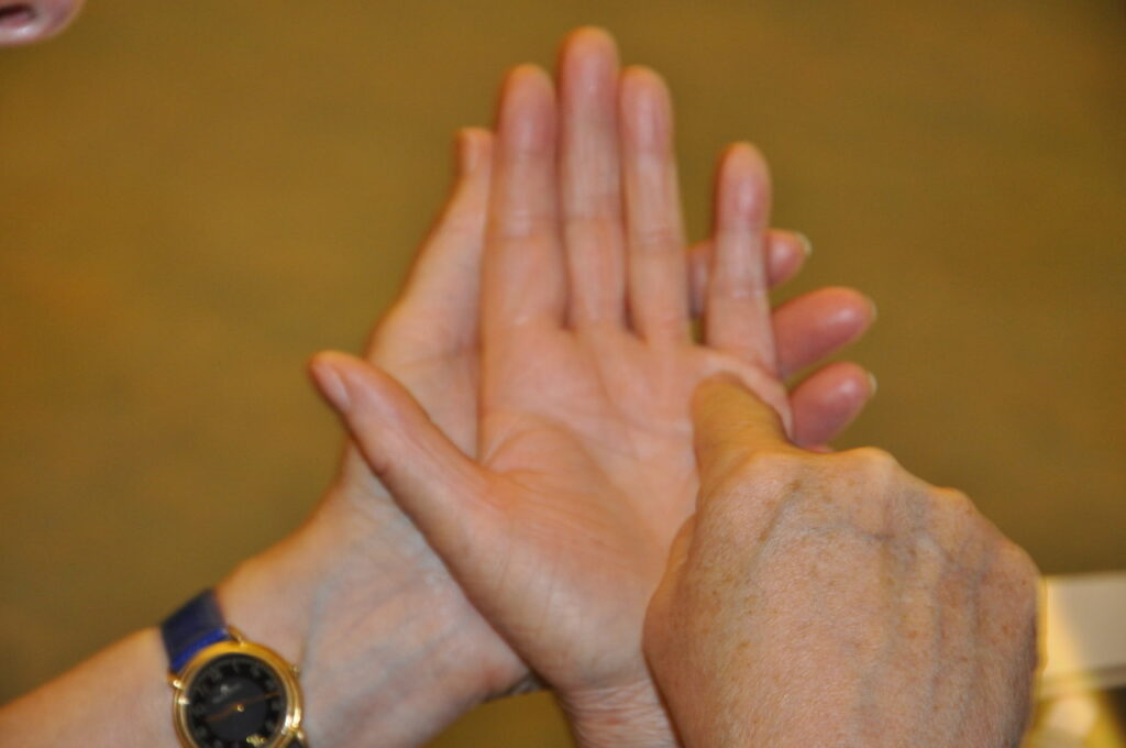 Zwei Hände, eine zeigt auf die Handfläche der anderen, die eine Uhr trägt.