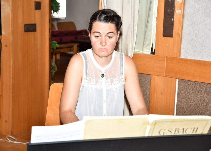 Eine Person sitzt am Klavier und schaut auf die Notenblätter.